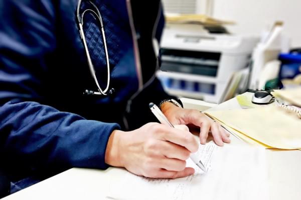 Médecin avec un stétoscope autour du cou signant un document