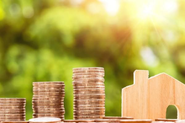 3 piles de pièces de monnaies à côté d'une maisonette en bois