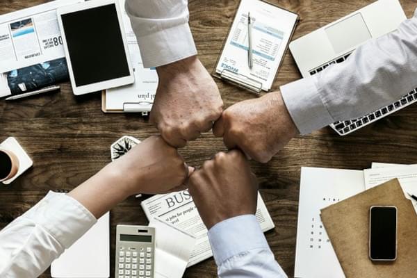 4 personnes faisant un check avec leur poing au dessus d'une table