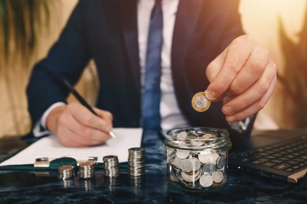 Personne en costume mettant une pièce de monnaie dans un pot en verre