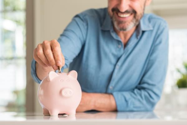 Homme metant une pièce de monnaie dans une tirelire